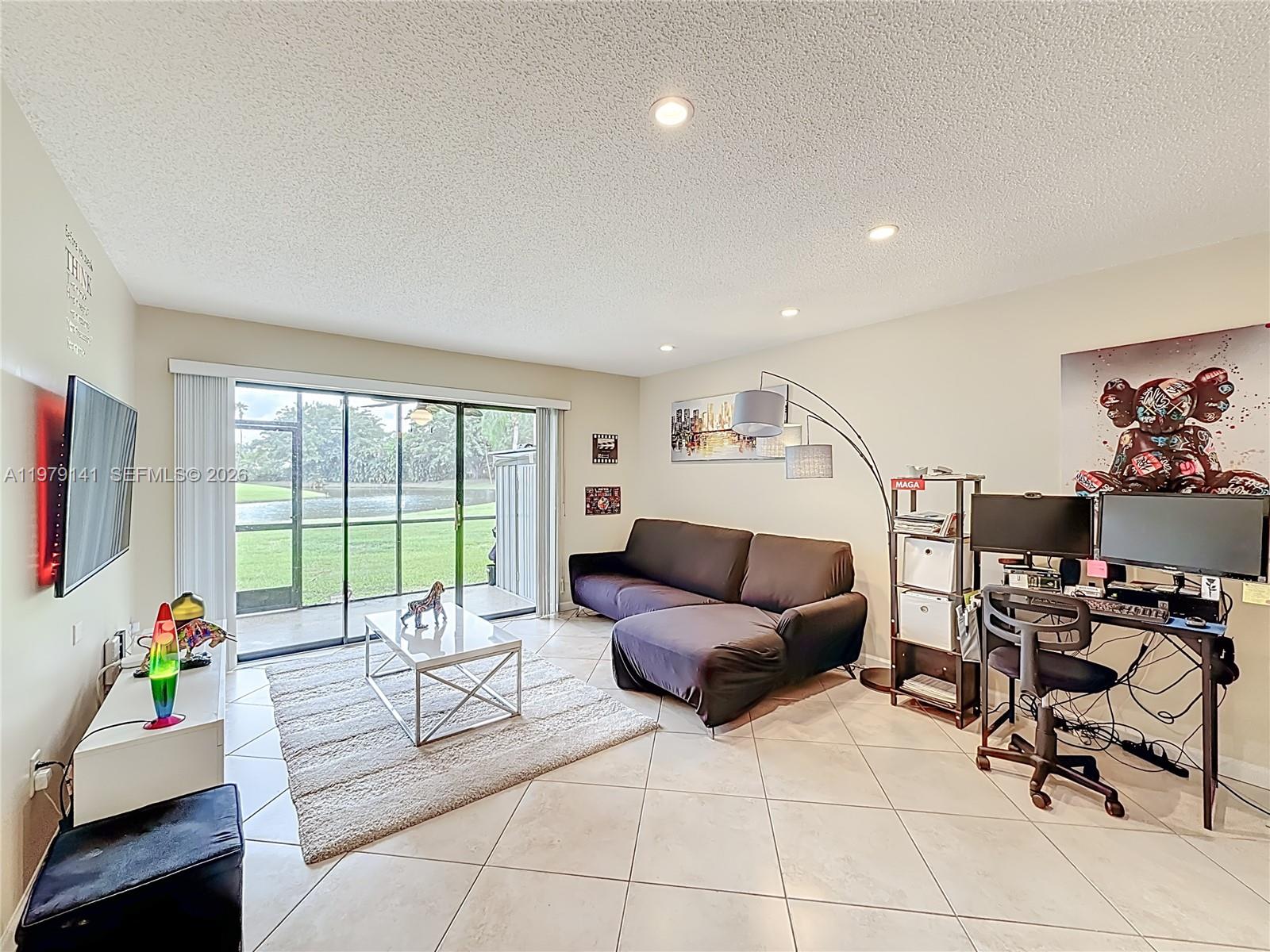A living room features tile floors, a sectional sofa, a desk, and sliding glass doors — 8422 E Boca Glades Blvd E # 8422, Boca Raton FL 33434, BOCA RATON, FL