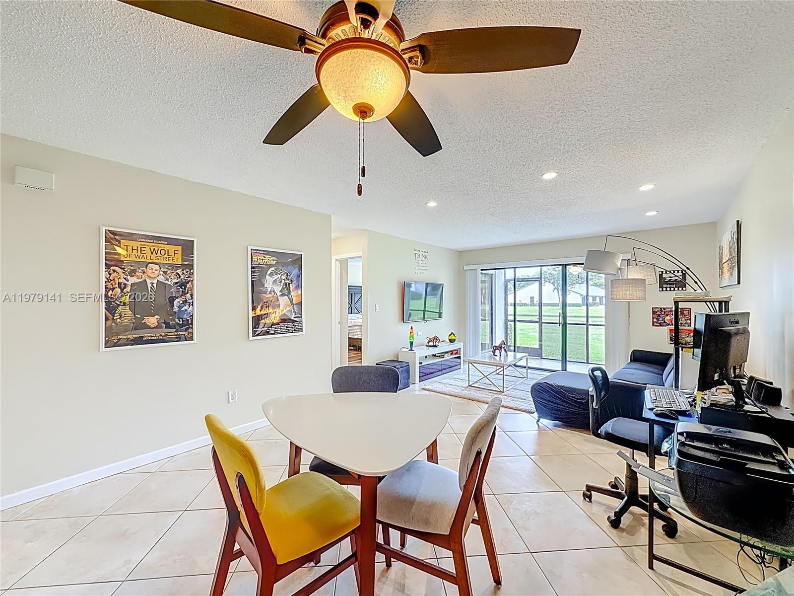 A dining area with a triangular table opens into a living room with tile floors — 8422 E Boca Glades Blvd E # 8422, Boca Raton FL 33434, BOCA RATON, FL