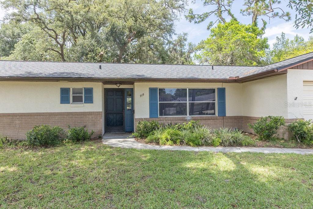A single-story house with a brick and stucco exterior, blue shutters, and a front walkway — 919 E MICHIGAN AVENUE, DELAND, FL