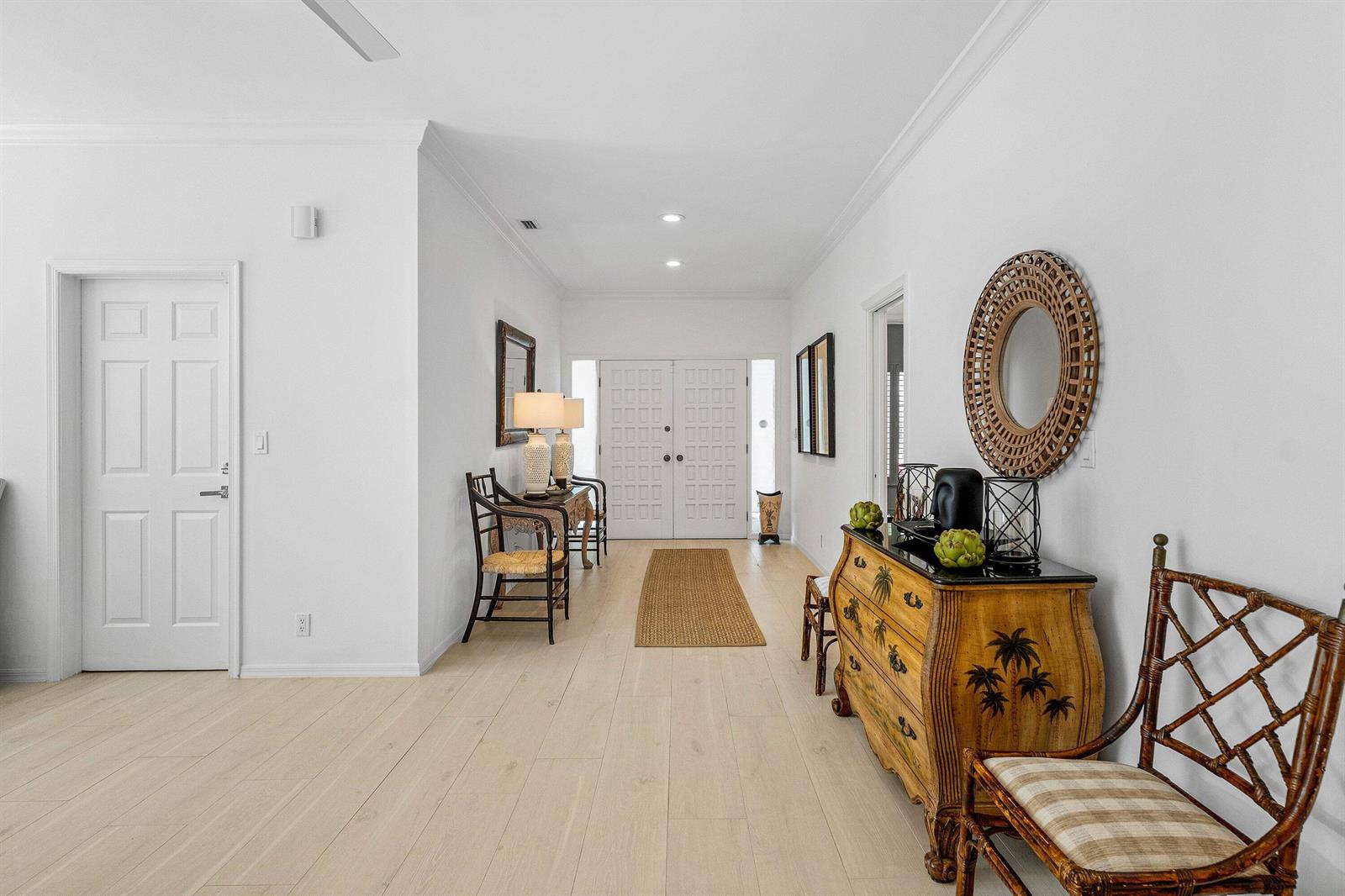 A bright entryway features light wood floors, a decorative chest, and a round wall mirror — 1100 N Ocean Boulevard, Gulf Stream FL 33483, GULF STREAM, FL