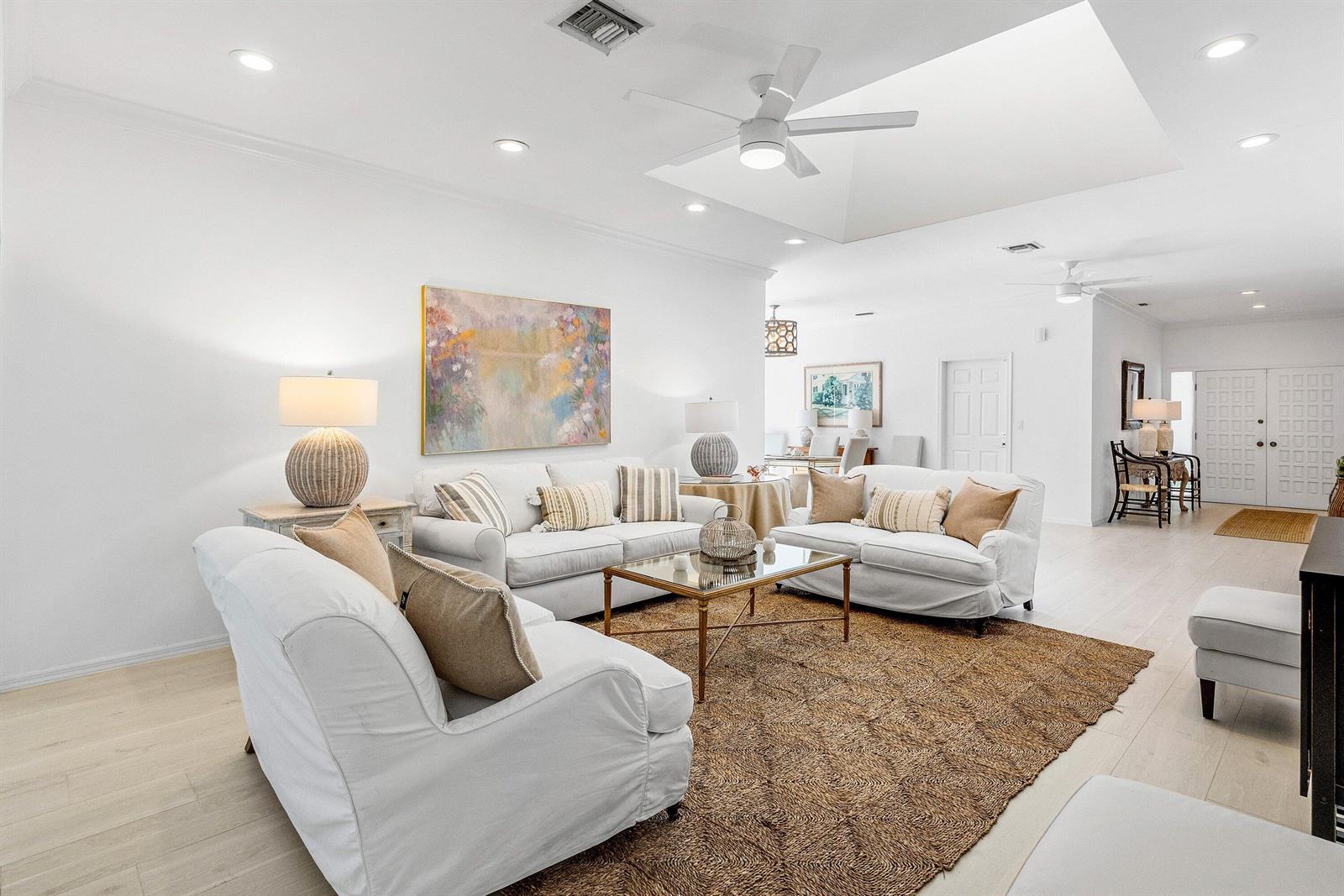 A bright living room features white sofas, a glass coffee table, and a textured rug — 1100 N Ocean Boulevard, Gulf Stream FL 33483, GULF STREAM, FL