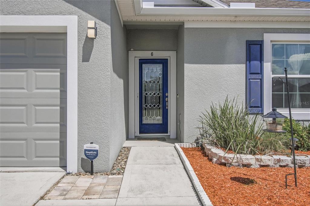 The exterior of a house features a blue front door, a garage, and landscaping — 6 OAKLEAF WAY, PALM COAST, FL