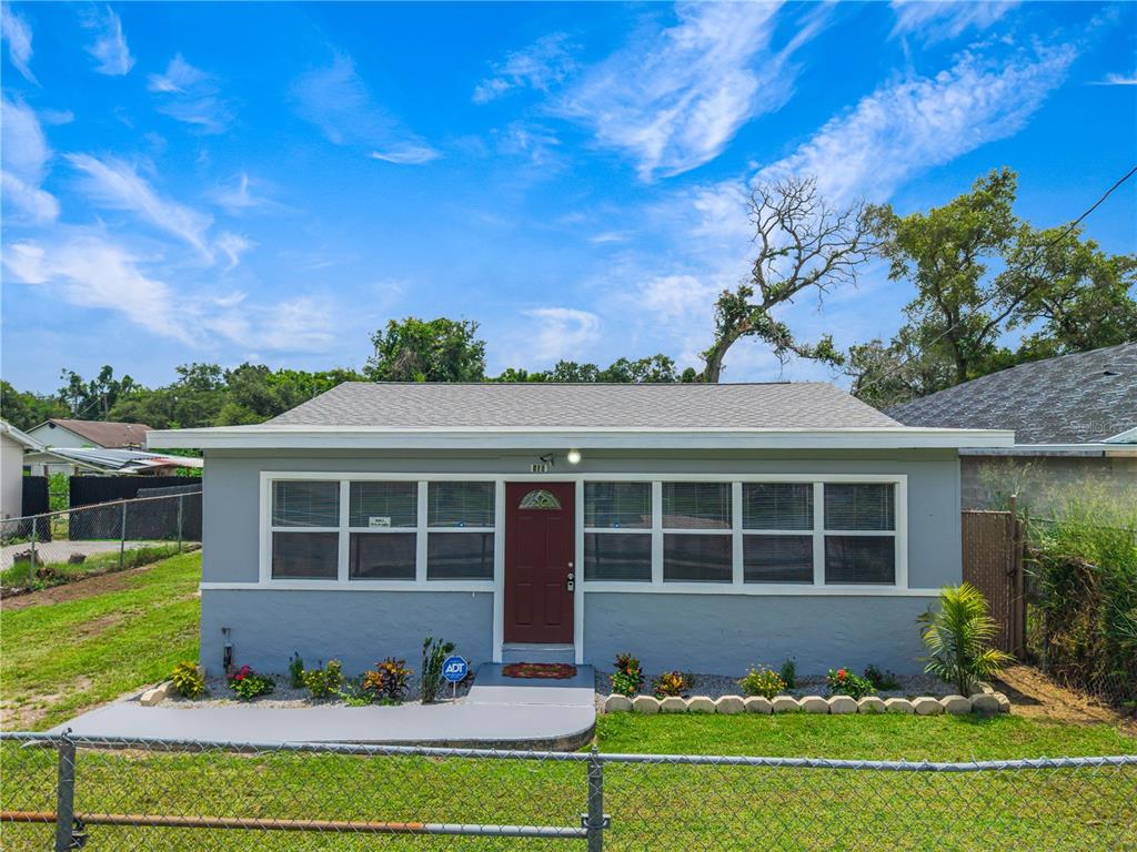 A single-story gray house with a red front door and a chain-link fence — 910 18TH STREET, ORLANDO, FL