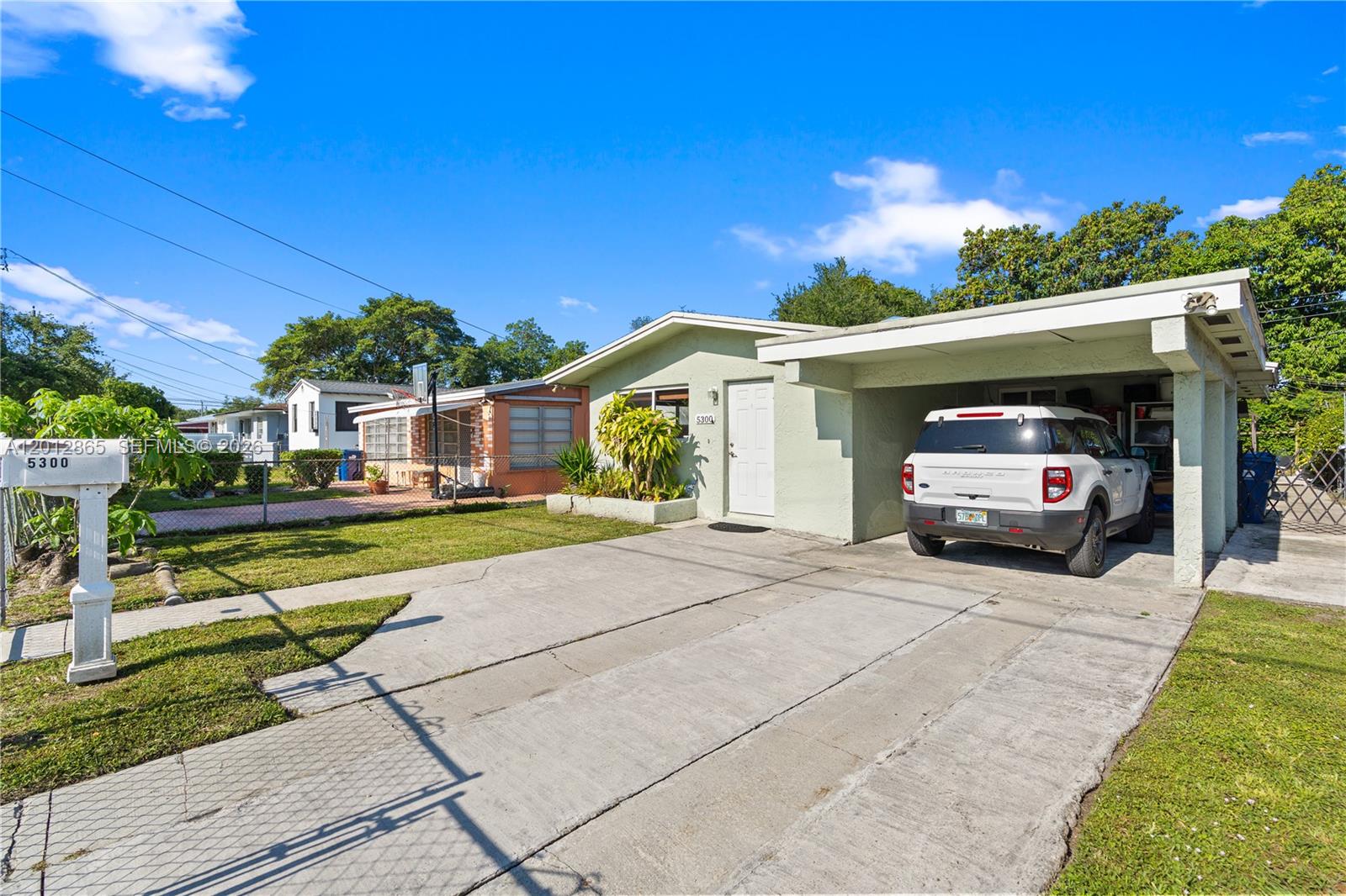 A light green single-story house features a concrete driveway and an attached carport — 5300 NW 30th Pl, Miami FL 33142, MIAMI, FL