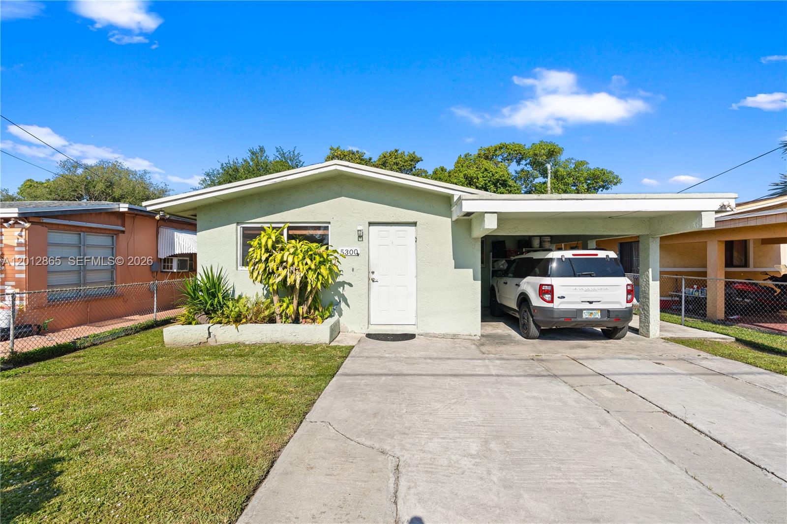 A light green single-story house features a concrete driveway, a carport, and a front planter — 5300 NW 30th Pl, Miami FL 33142, MIAMI, FL