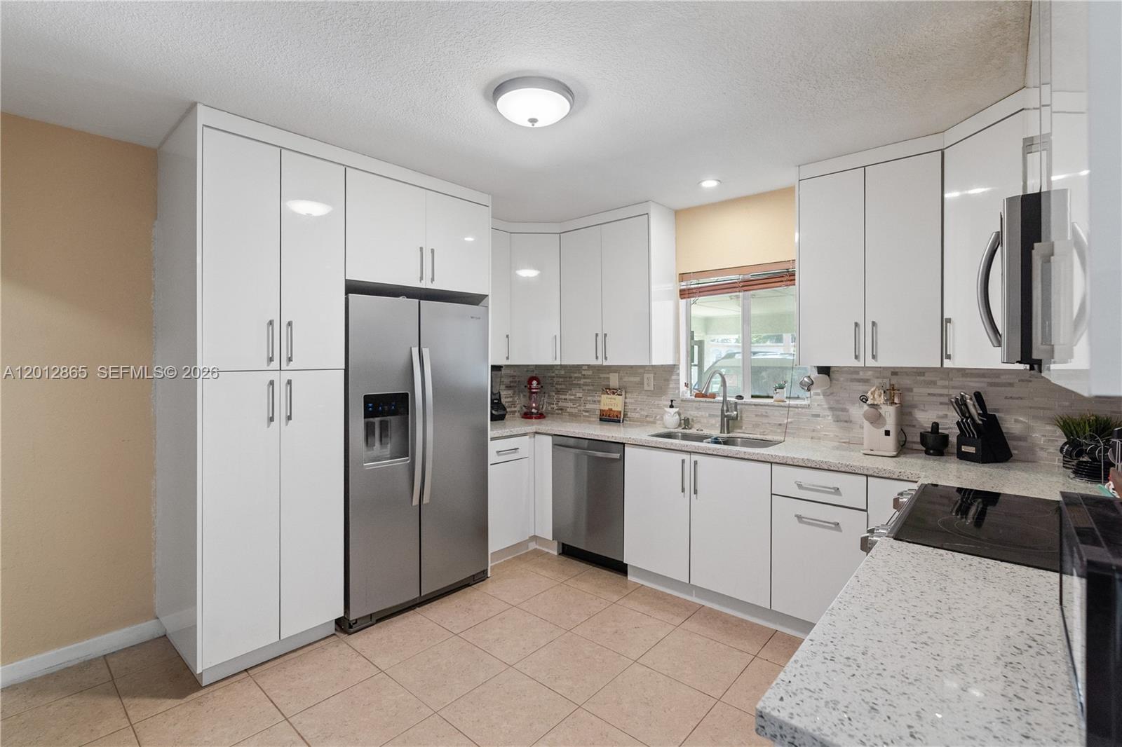 A kitchen features white cabinets, stainless steel appliances, a tiled backsplash, and a side console — 5300 NW 30th Pl, Miami FL 33142, MIAMI, FL