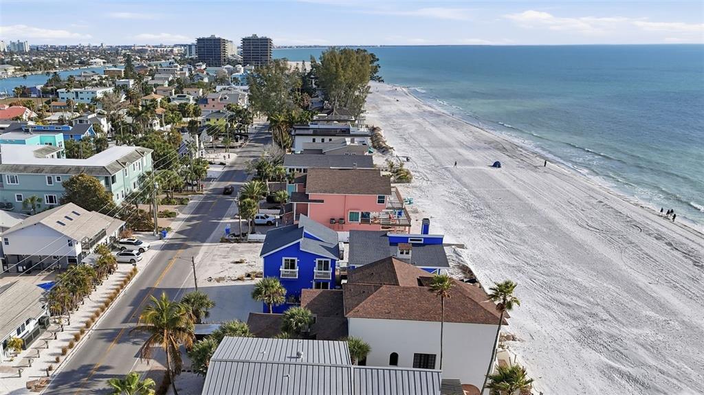 An aerial view shows a row of colorful beachfront houses along a sandy coastline — 8430 W GULF BOULEVARD, TREASURE ISLAND, FL