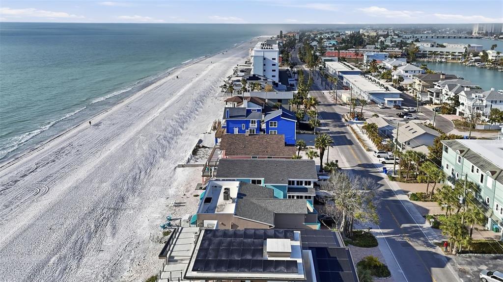 An aerial view shows beachfront houses along a coastal road next to the ocean — 8430 W GULF BOULEVARD, TREASURE ISLAND, FL
