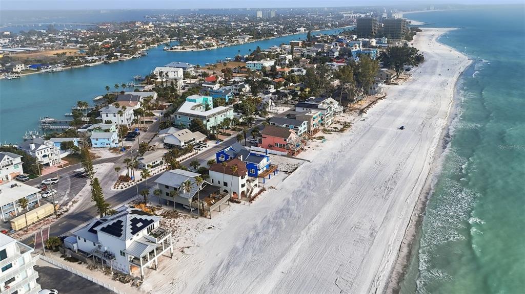 An aerial view shows beachfront houses and a wide sandy beach along the ocean — 8430 W GULF BOULEVARD, TREASURE ISLAND, FL