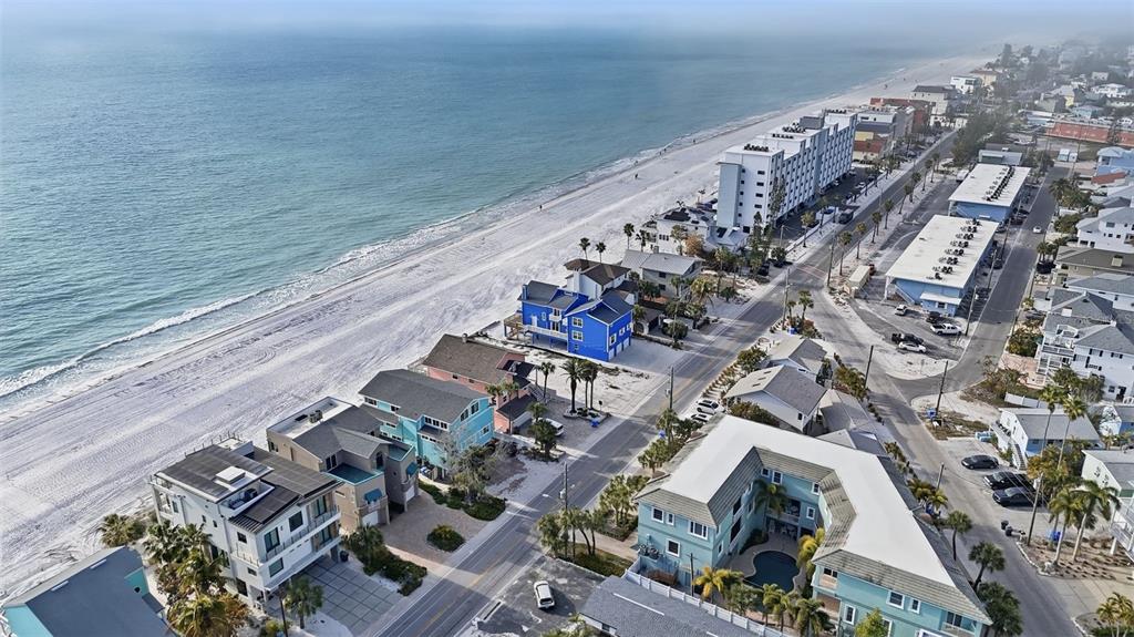 An aerial view shows beach houses and a multi-story building along a sandy coastline — 8430 W GULF BOULEVARD, TREASURE ISLAND, FL