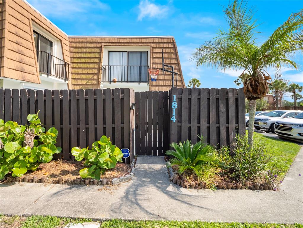 A two-story townhouse exterior features a brown wooden fence, a gated entrance, and a balcony — 1814 KAILEEN CIRCLE NE, PALM BAY, FL