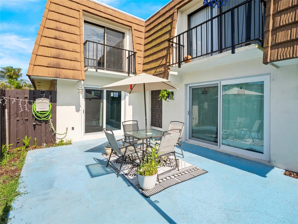 A patio with a dining set and umbrella sits outside a two-story building with balconies — 1814 KAILEEN CIRCLE NE, PALM BAY, FL