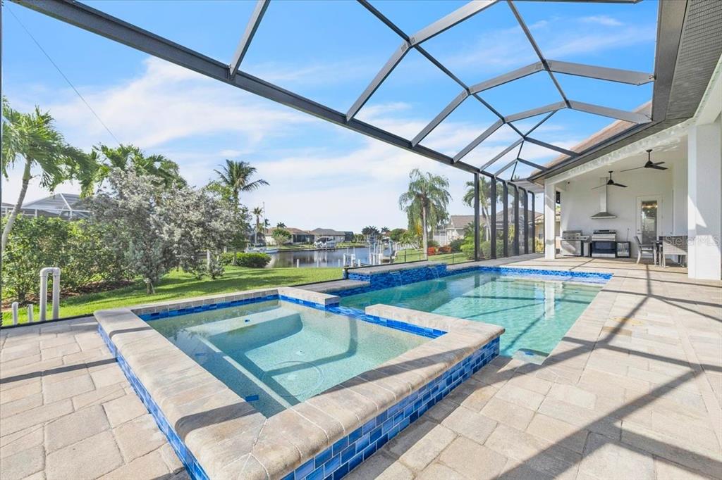 A screened-in patio features a swimming pool, a raised spa, and a view of water — 1323 PENGUIN COURT, PUNTA GORDA, FL