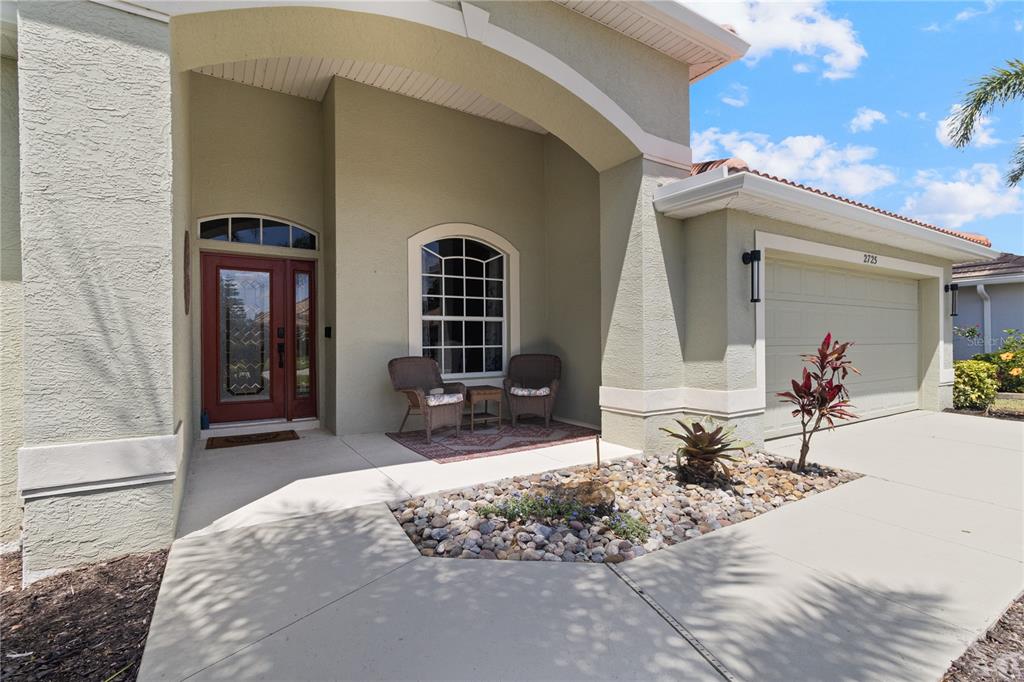 The exterior of a house features a covered entryway, a red front door, and a garage — 2725 ROYAL PALM DRIVE, NORTH PORT, FL