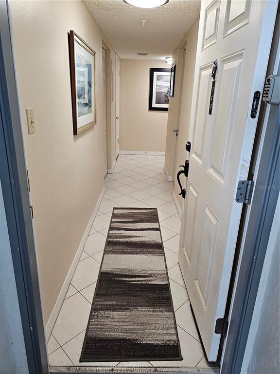A narrow entryway hallway features white tile floors, a striped runner rug, and beige walls — 5207 S ATLANTIC AVENUE UNIT 722, NEW SMYRNA BEACH, FL