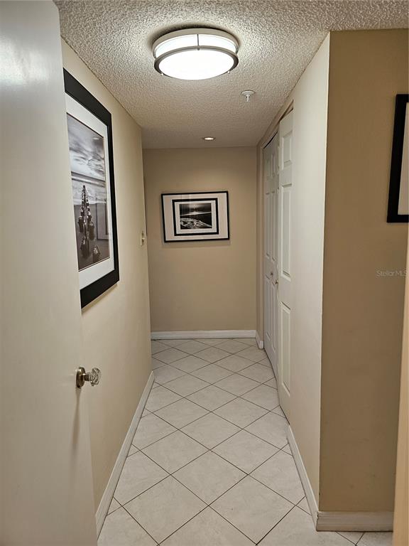 A hallway with beige walls, white tile flooring, and two framed black-and-white photographs — 5207 S ATLANTIC AVENUE UNIT 722, NEW SMYRNA BEACH, FL