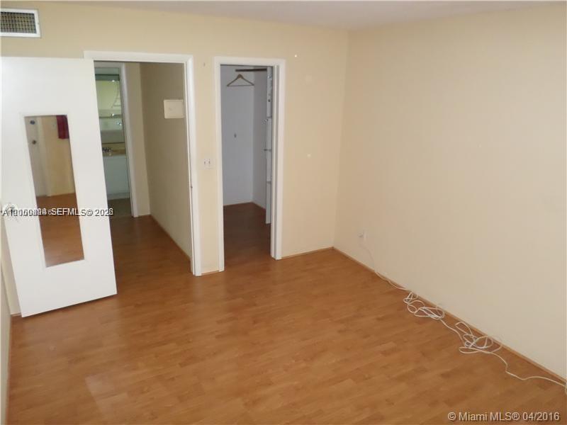An interior room features light-colored walls, wood-look flooring, a closet, and an open doorway — HOLLYWOOD, FL