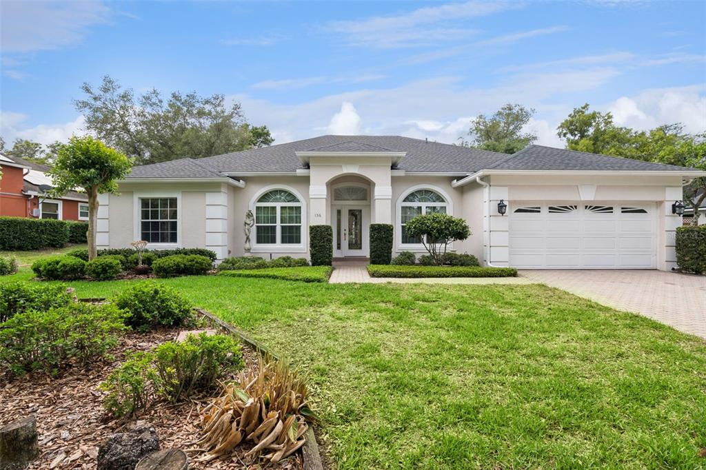 A single-story house with a white stucco exterior, arched windows, and a two-car garage — 156 SEVILLE CHASE DRIVE, WINTER SPRINGS, FL