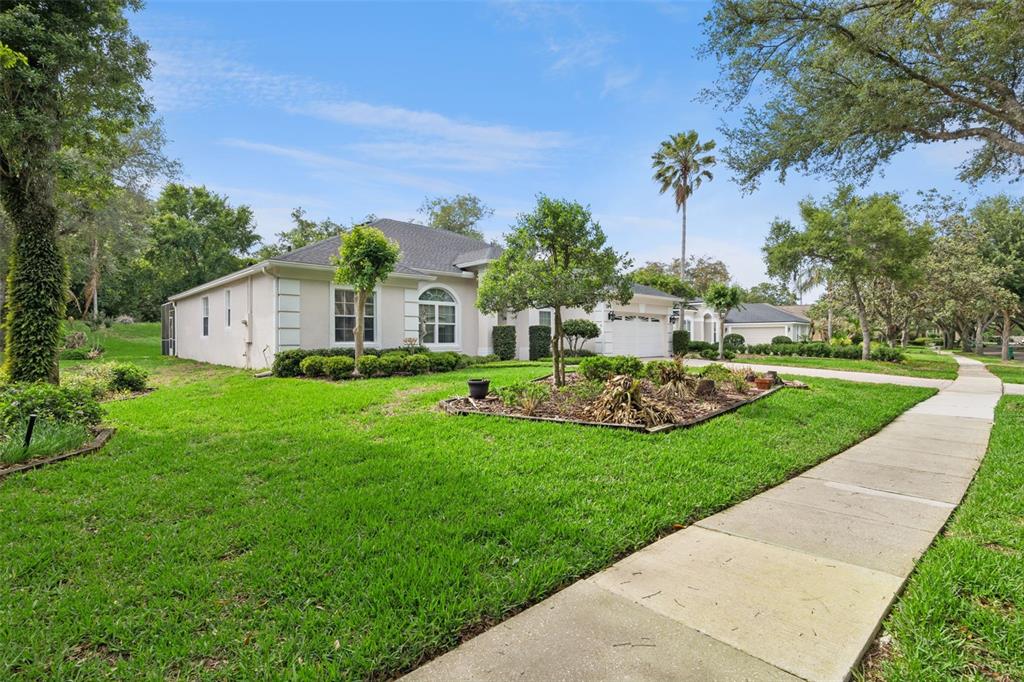A single-story house with a light-colored exterior, a garage, and a landscaped front yard — 156 SEVILLE CHASE DRIVE, WINTER SPRINGS, FL