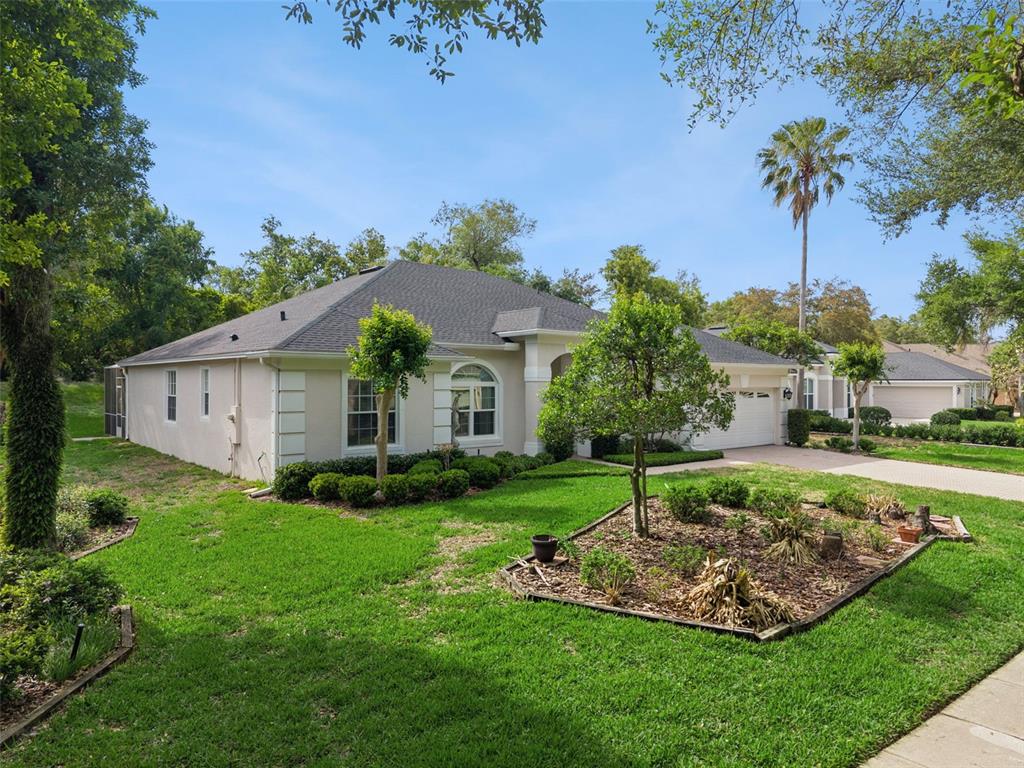 A single-story beige house with a dark shingled roof, a garage, and a landscaped yard — 156 SEVILLE CHASE DRIVE, WINTER SPRINGS, FL