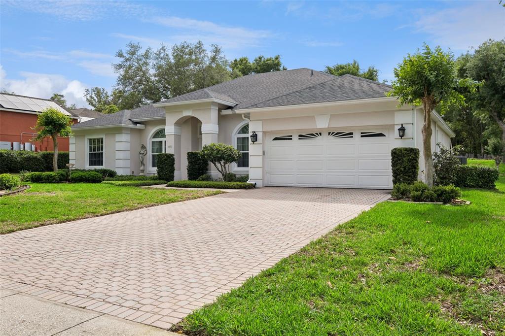 A single-story house with a beige stucco exterior, a two-car garage, and a paved driveway — 156 SEVILLE CHASE DRIVE, WINTER SPRINGS, FL