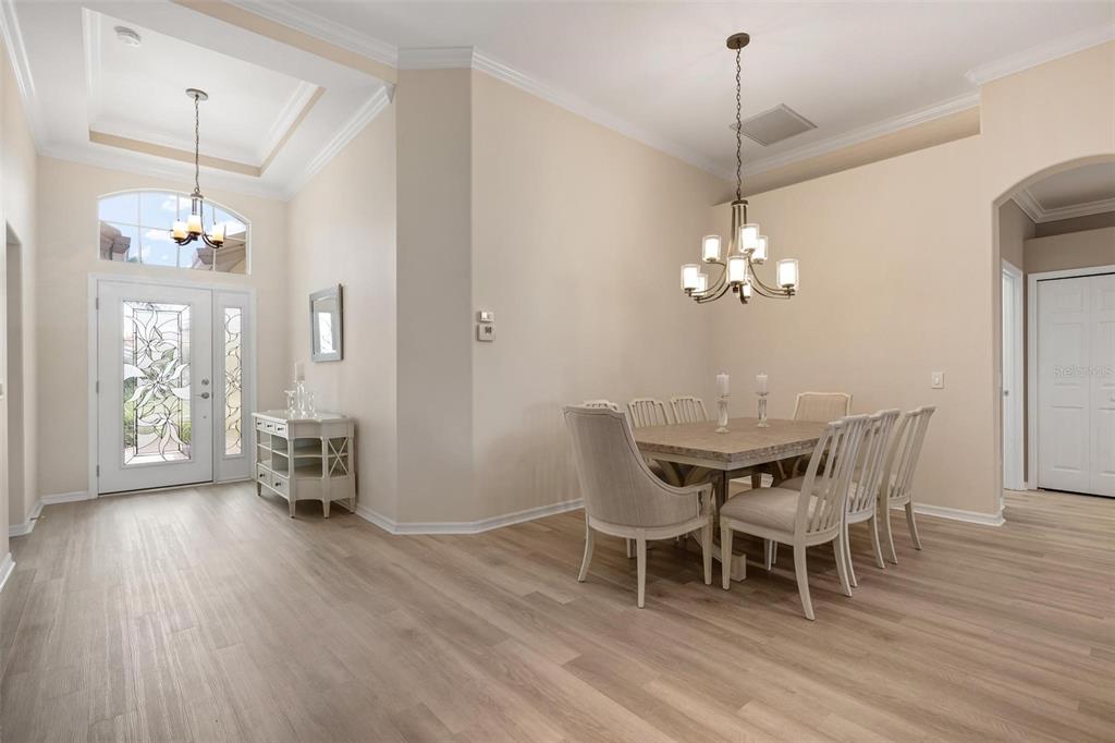 A dining room with light wood floors, a chandelier, and a table with six chairs — 748 BACK NINE DRIVE, VENICE, FL