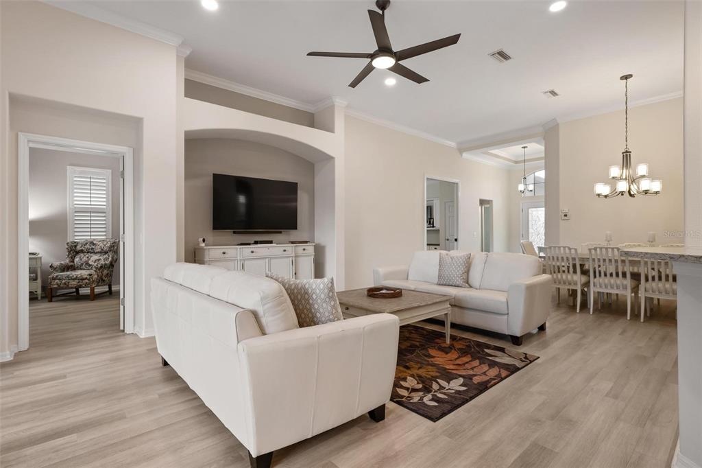 A living room features white sofas, a television in an arched alcove, and wood flooring — 748 BACK NINE DRIVE, VENICE, FL