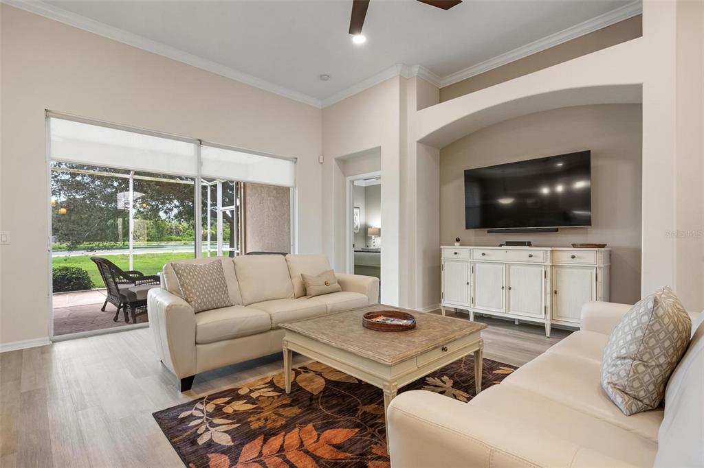 A living room features light-colored sofas, a wooden coffee table, and a wall-mounted television — 748 BACK NINE DRIVE, VENICE, FL