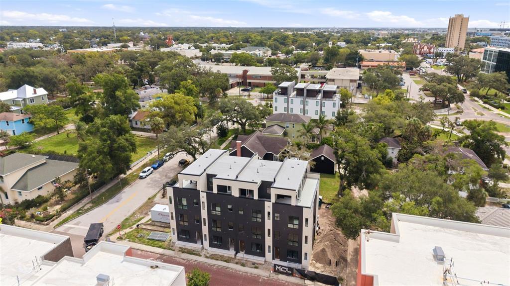 An aerial view shows a modern multi-story apartment building surrounded by houses and trees — 2119 N OLA AVENUE UNIT 2, TAMPA, FL