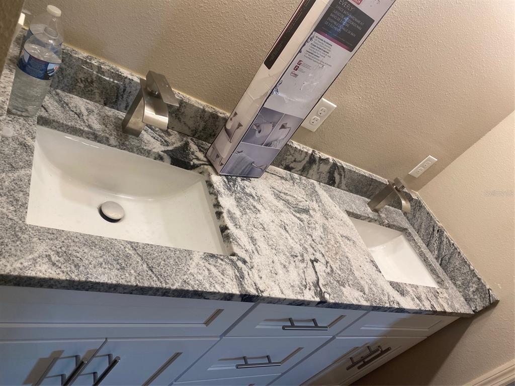 A double vanity bathroom features white cabinets, granite countertops, and two undermount sinks — 14910 LAURIE LANE, TAMPA, FL