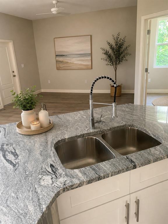 A kitchen island with a stainless steel double sink and granite countertop faces a room — 14910 LAURIE LANE, TAMPA, FL