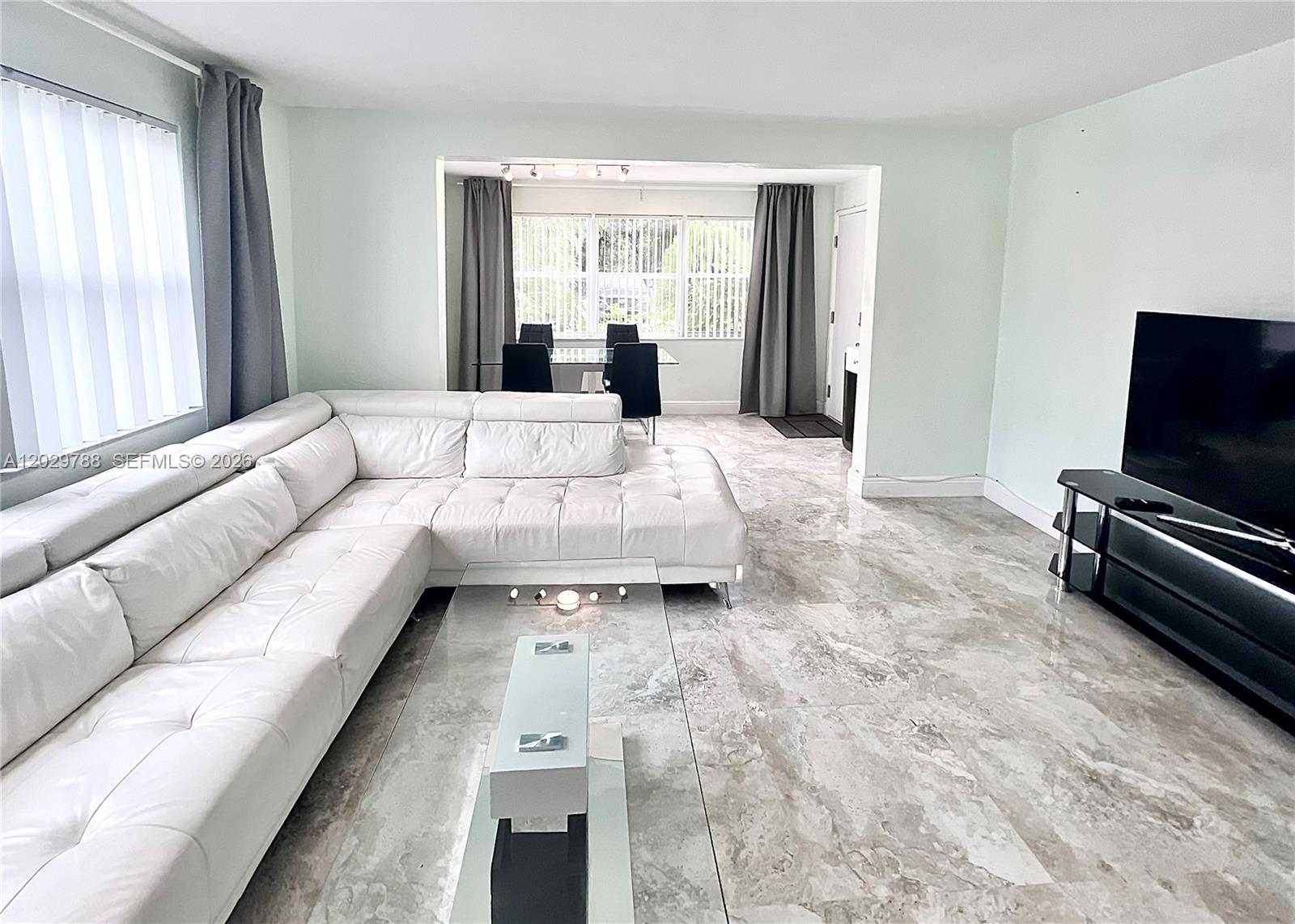 A living room features a white sectional sofa, marble-look tile floors, and a dining area — 1940 Adams St, Hollywood FL 33020, HOLLYWOOD, FL