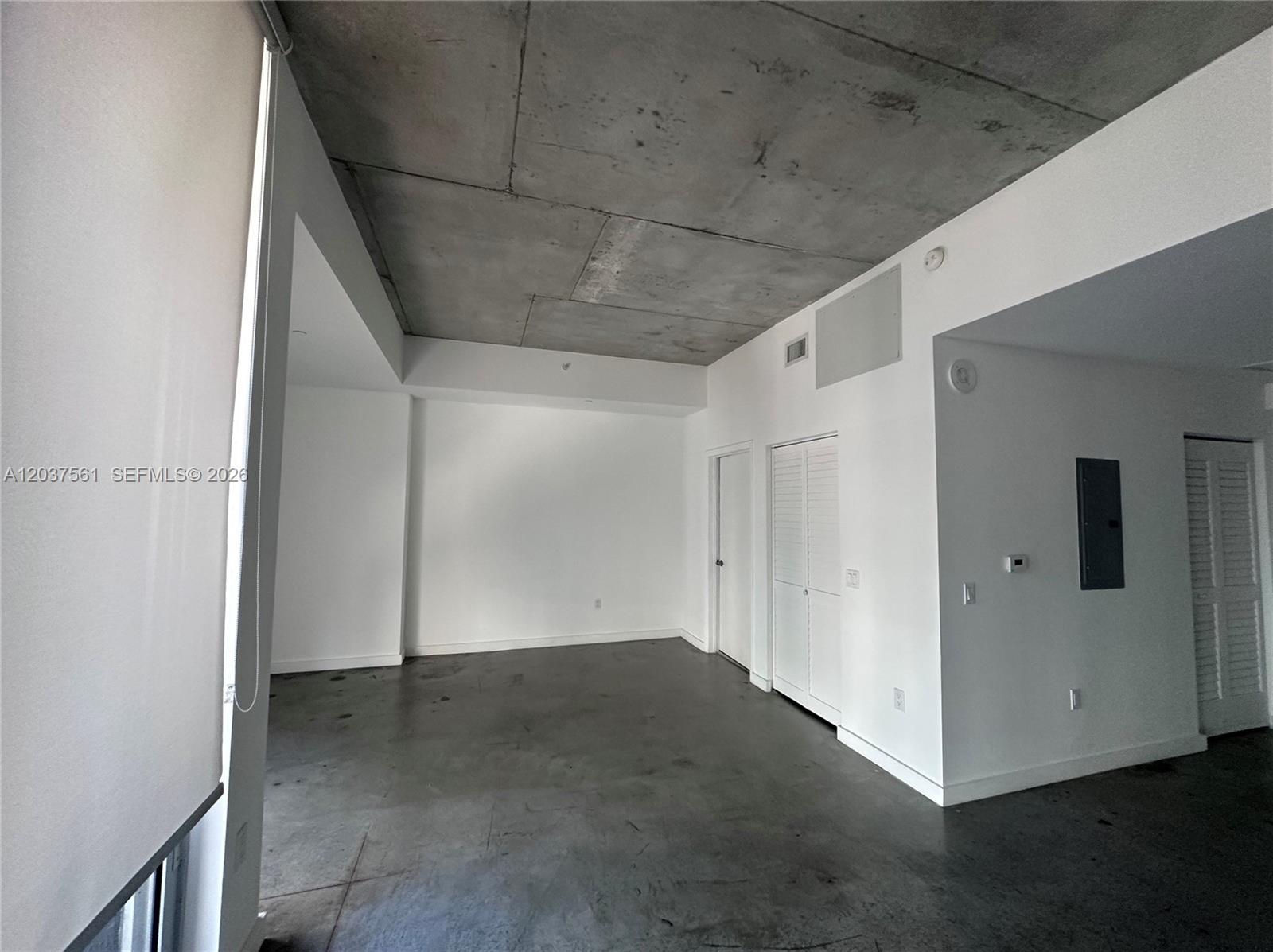 An empty room features a raw concrete ceiling, polished concrete floors, and white walls — 151 SE 1st St # 2405, Miami FL 33131, MIAMI, FL