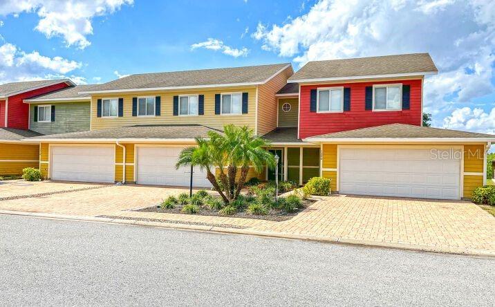 A multi-unit residential building features colorful siding, multiple garage doors, and a paved driveway — 1125 EVERGREEN COURT, WINTER HAVEN, FL