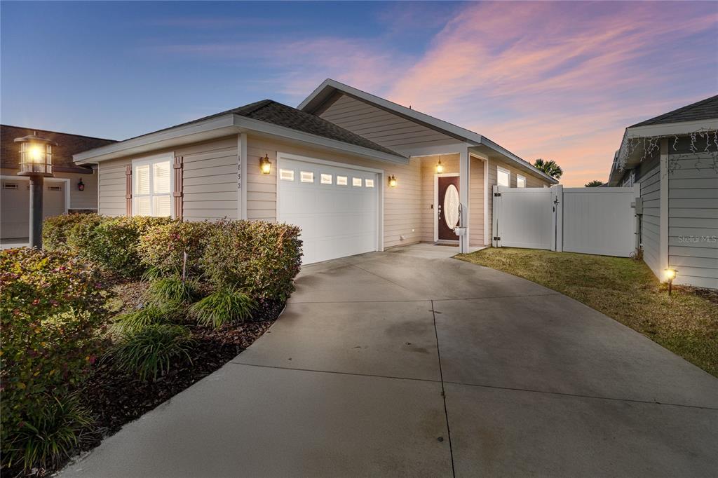 A single-story house with beige siding, a white garage door, and a concrete driveway — 1852 SW 246TH DRIVE, NEWBERRY, FL