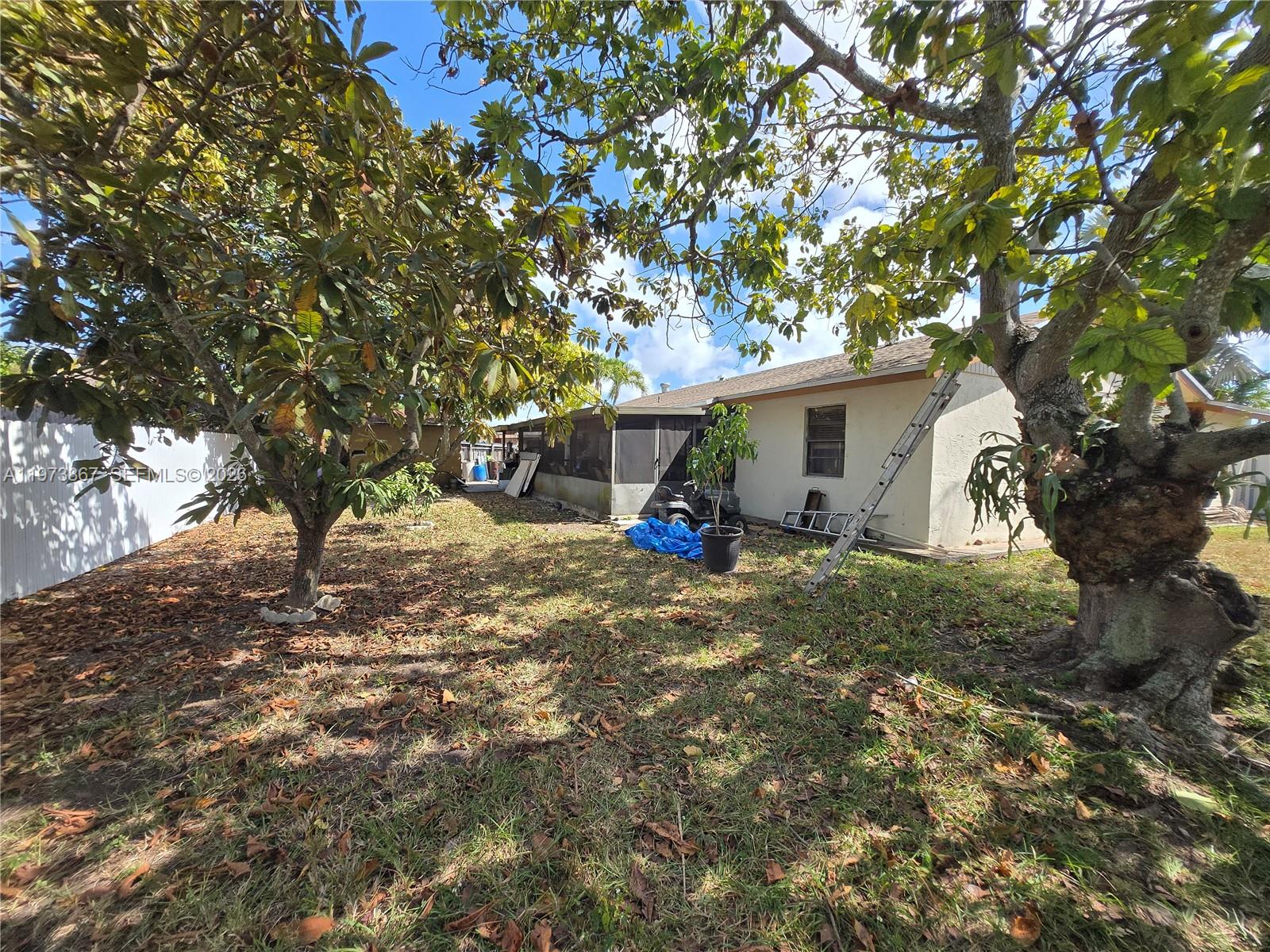 A backyard features a house with a screened porch, a ladder, and several large trees — 13377 SW 46th Ln, Miami FL 33175, MIAMI, FL