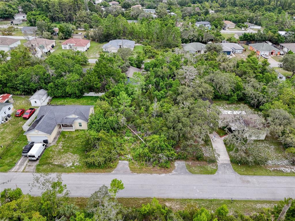 An aerial view shows two houses separated by a large, wooded vacant lot — TINLEY LOTS 71, 72, & 73, NEW PORT RICHEY, FL