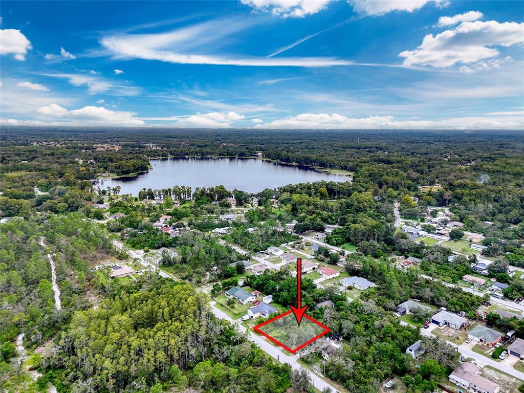 An aerial view shows a vacant, rectangular residential lot outlined in red near a lake — TINLEY LOTS 71, 72, & 73, NEW PORT RICHEY, FL