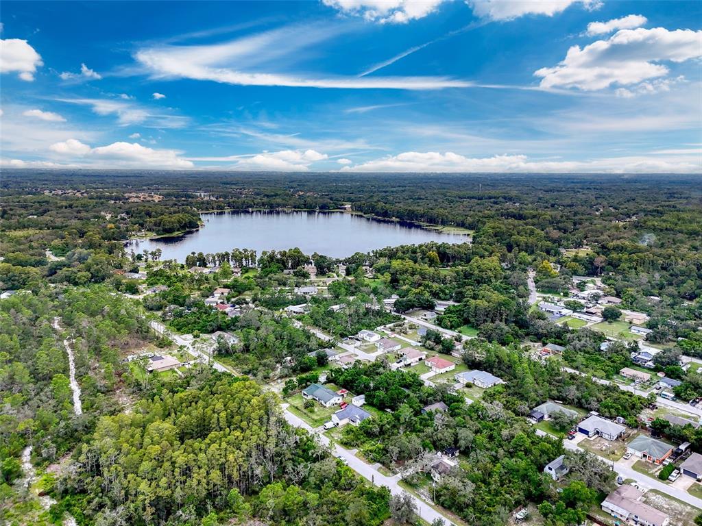 An aerial view shows a lake surrounded by residential homes and dense forest under a sky — TINLEY LOTS 71, 72, & 73, NEW PORT RICHEY, FL