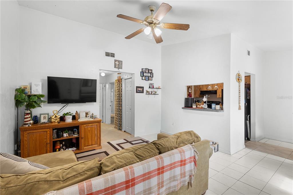 A living room features a tan sofa, a wooden media console, and a ceiling fan — 2038 SW 70TH TERRACE, GAINESVILLE, FL