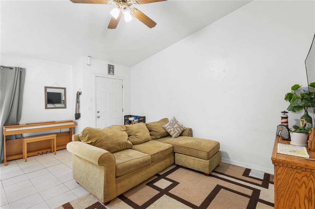 A living room features a tan sectional sofa, a ceiling fan, and a wooden piano — 2038 SW 70TH TERRACE, GAINESVILLE, FL