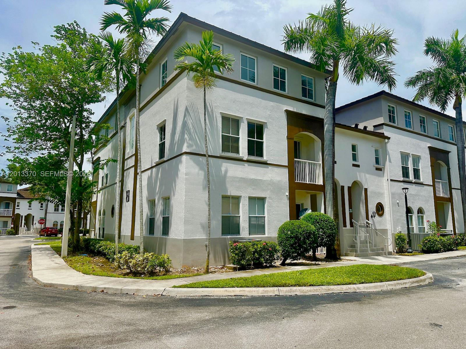 A three-story white stucco townhouse with palm trees and a sidewalk in front — 4371 SW 160th Ave # 203, Miramar FL 33027, MIRAMAR, FL