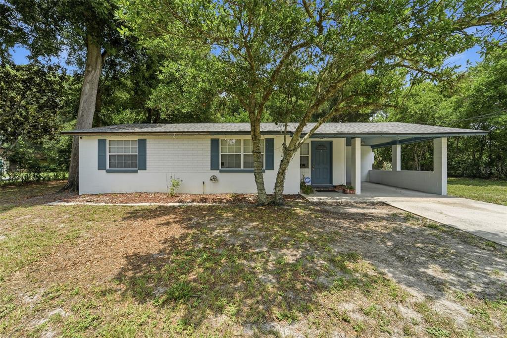 A single-story white brick house features a gray roof, blue shutters, and an attached carport — 44 VOLUSIA DRIVE, DEBARY, FL