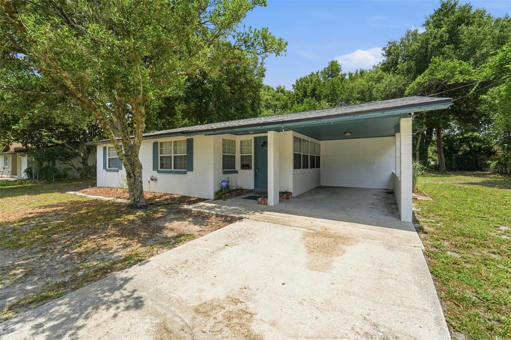 A single-story house with a white exterior, a blue front door, and an attached carport — 44 VOLUSIA DRIVE, DEBARY, FL