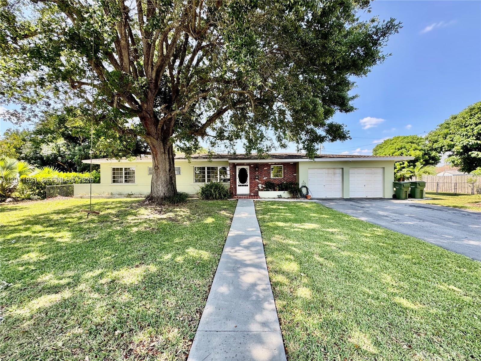 A single-story house with a large oak tree, brick accents, and a two-car garage — 434 NW 20th St, Homestead FL 33030, HOMESTEAD, FL