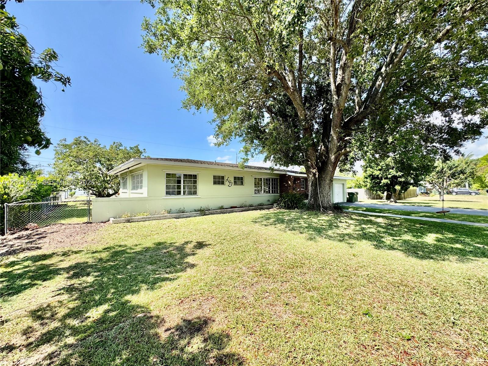 A light green single-story house sits on a grassy lot with a large oak tree — 434 NW 20th St, Homestead FL 33030, HOMESTEAD, FL