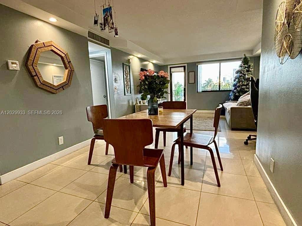 A dining area features a wooden table, four chairs, and a wall-mounted hexagonal mirror — 301 Golden Isles Dr # 406, Hallandale Beach FL 33009, HALLANDALE BEACH, FL