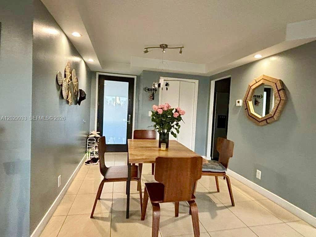 A dining room features a wooden table, four chairs, and a decorative wall mirror — 301 Golden Isles Dr # 406, Hallandale Beach FL 33009, HALLANDALE BEACH, FL