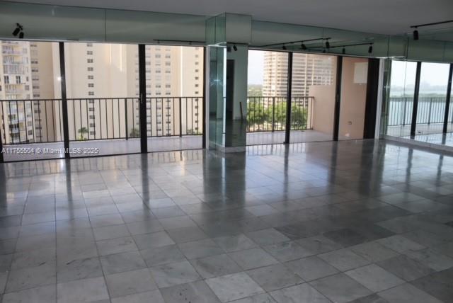 An empty room with large windows, a balcony, and light-colored square floor tiles — 1800 NE 114th St # 1108, Miami FL 33181, MIAMI, FL