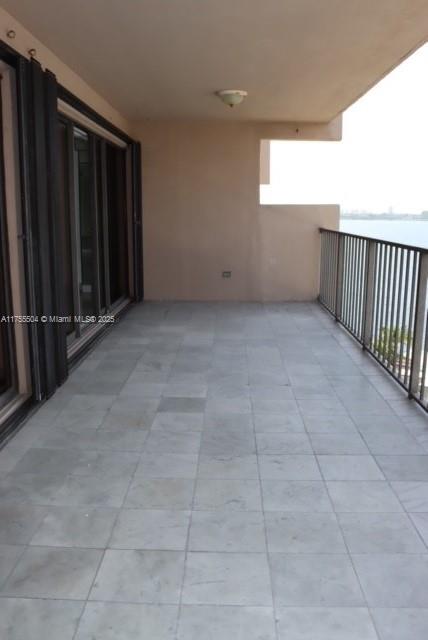 A spacious balcony with light-colored tile flooring, a metal railing, and sliding glass doors — 1800 NE 114th St # 1108, Miami FL 33181, MIAMI, FL